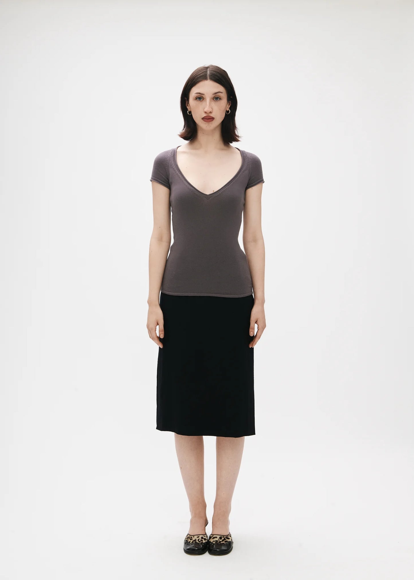Woman wearing a gray top and black skirt on a white background