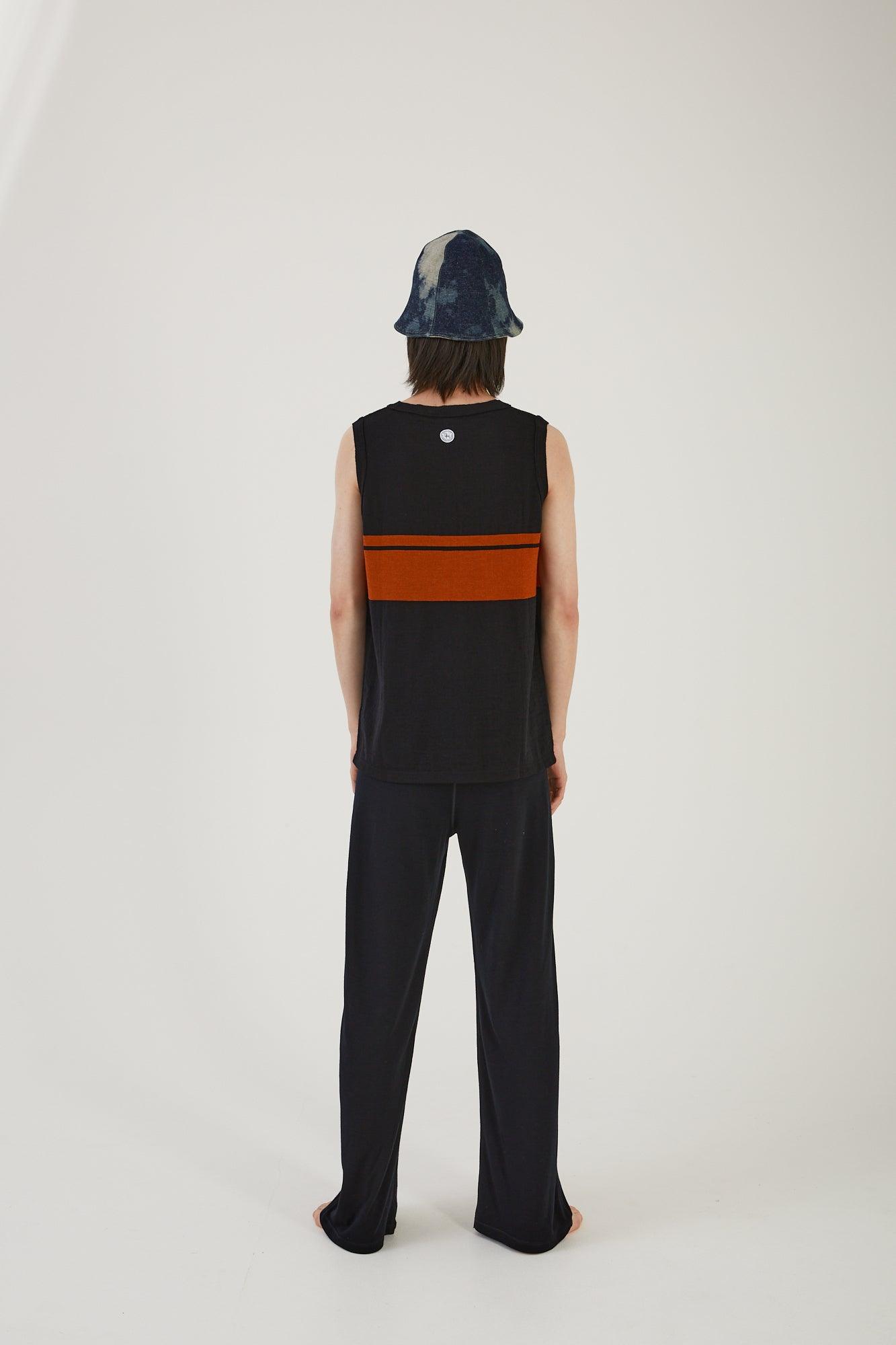 A person wearing merino wool track pants, a merino wool striped vest and an upcycled wool blanket and denim hat