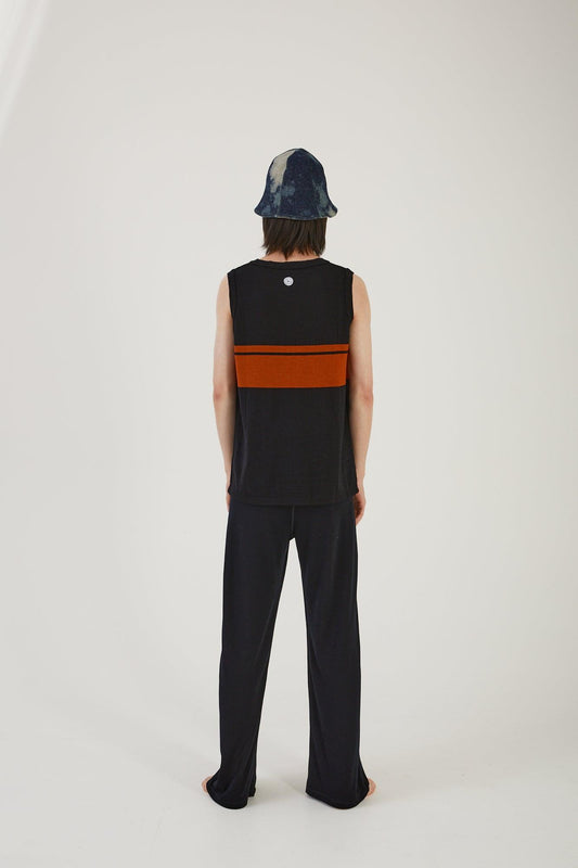 A person wearing merino wool track pants, a merino wool striped vest and an upcycled wool blanket and denim hat