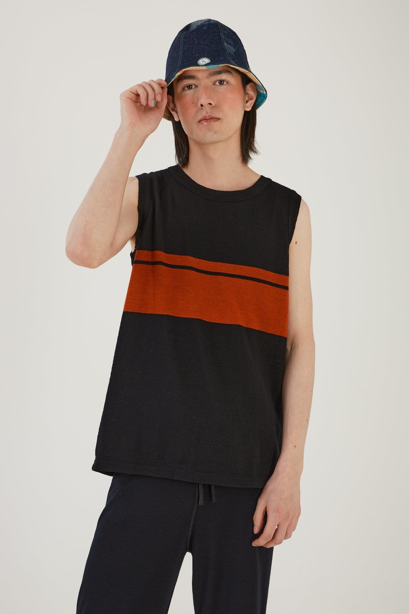 A person wearing merino wool track pants, a merino wool striped vest and an upcycled wool blanket and denim hat