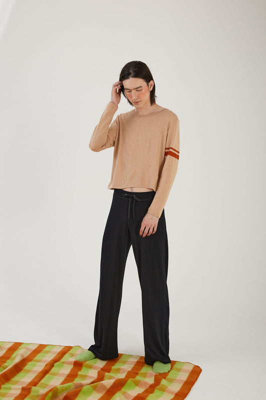 A person standing on the edge of a wool blanket wearing merino wool socks, merino wool track pants and a merino wool sweater