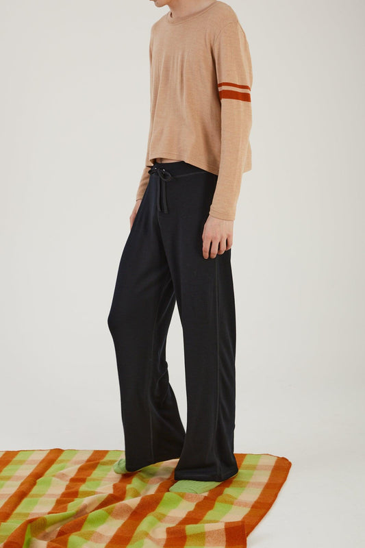 A person standing on the edge of a wool blanket wearing merino wool socks, merino wool track pants and a merino wool sweater