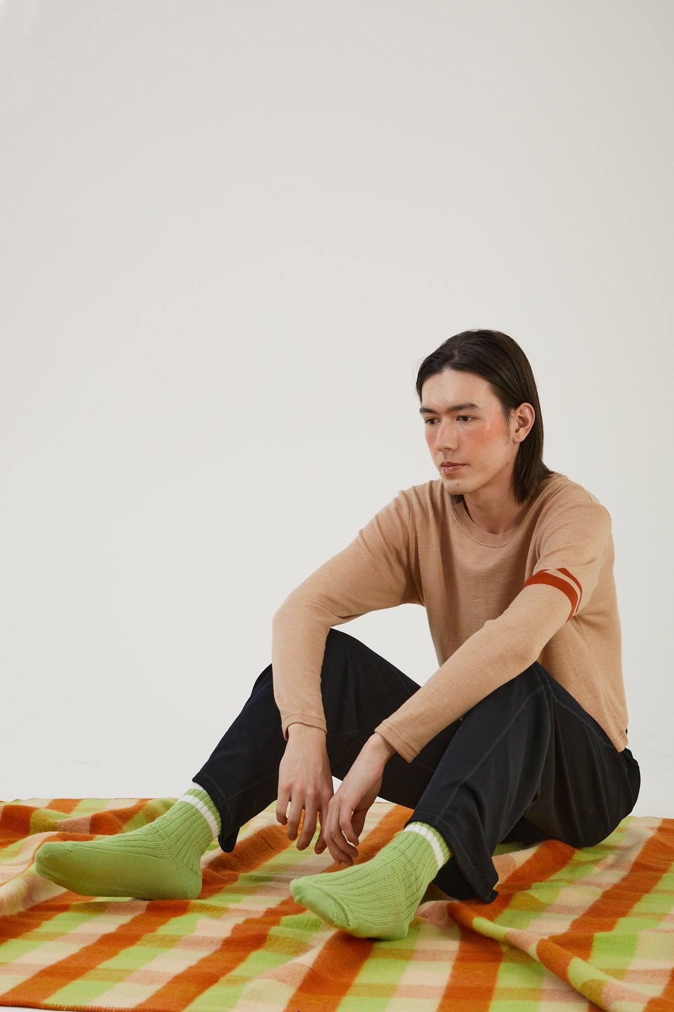 A person sitting on a wool blanket wearing merino wool socks and merino wool clothing