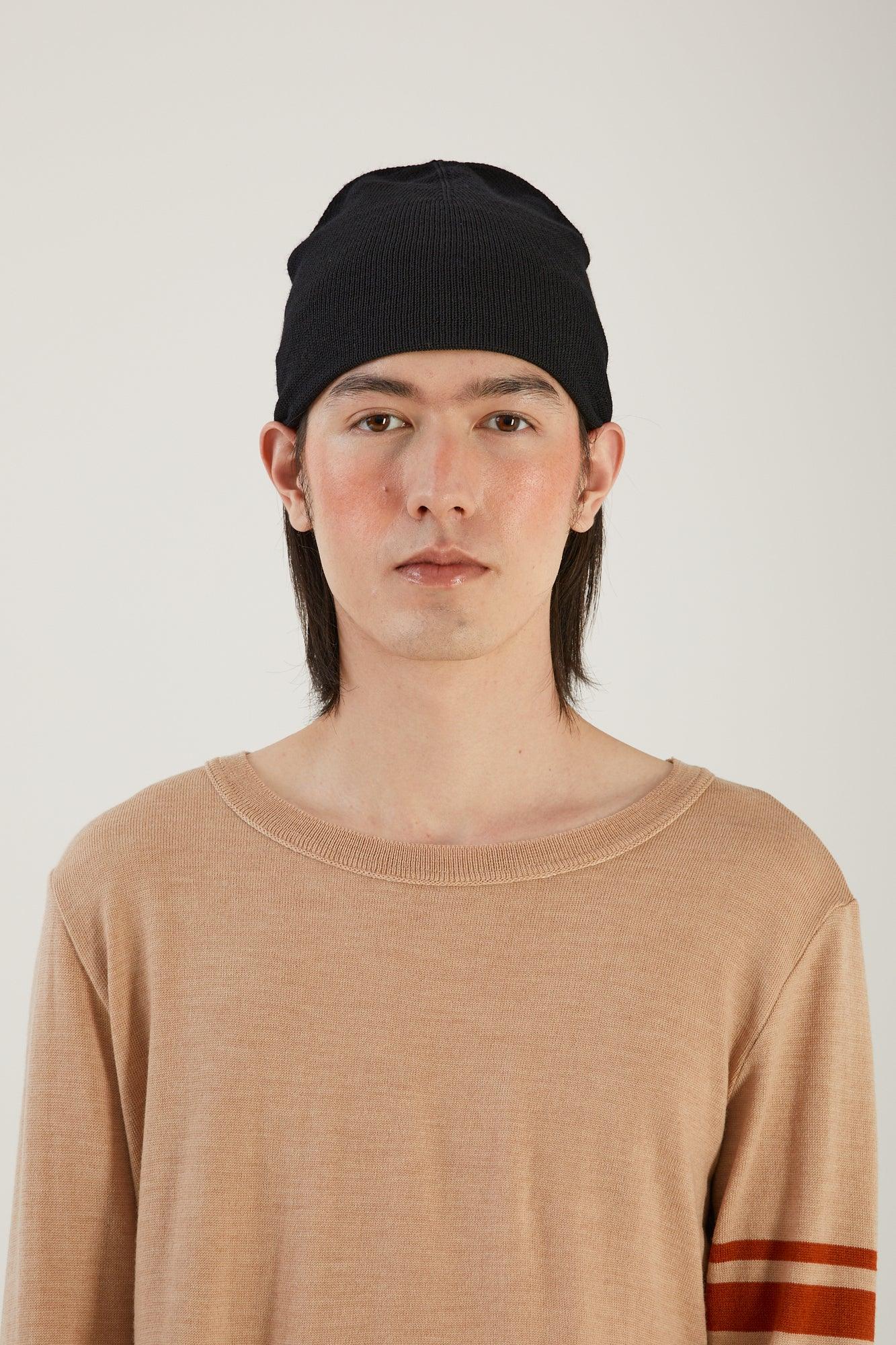 A person visible from the waist up wearing a merino wool sweater and black merino wool beanie