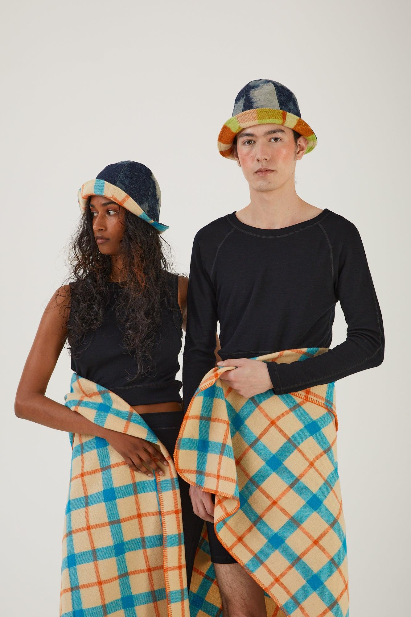 Two people wearing merino wool clothing and upcycled deadstock denim and wool blanket hats with a wool blanket wrapped around their waists