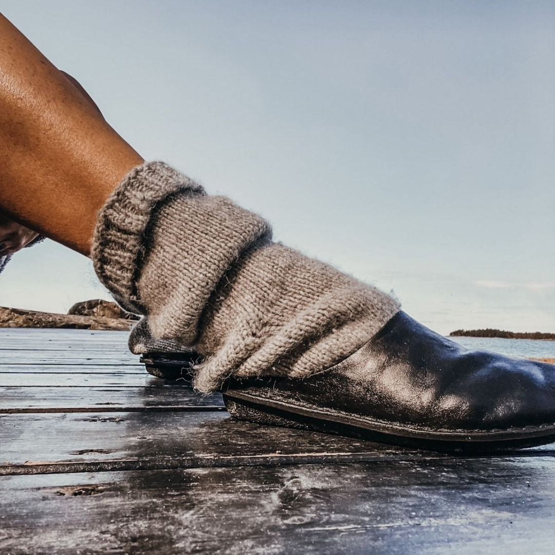 A persons leg wearing a grey wool sock and a leather VIBAe slide