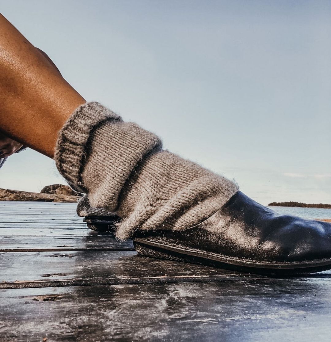 A persons leg wearing a grey wool sock and a leather VIBAe slide