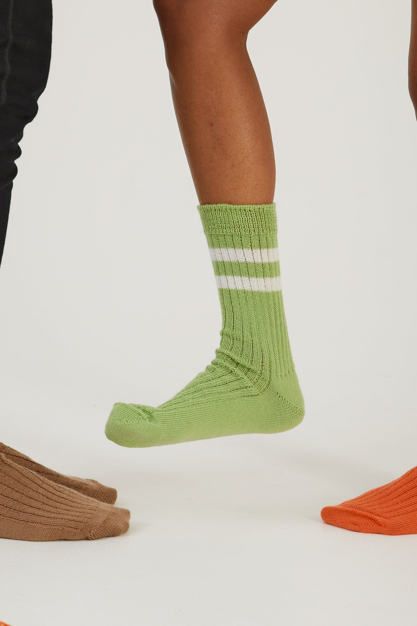 A foot fully visible wearing a merino wool sock and three feet half in the frame also wearing merino wool socks