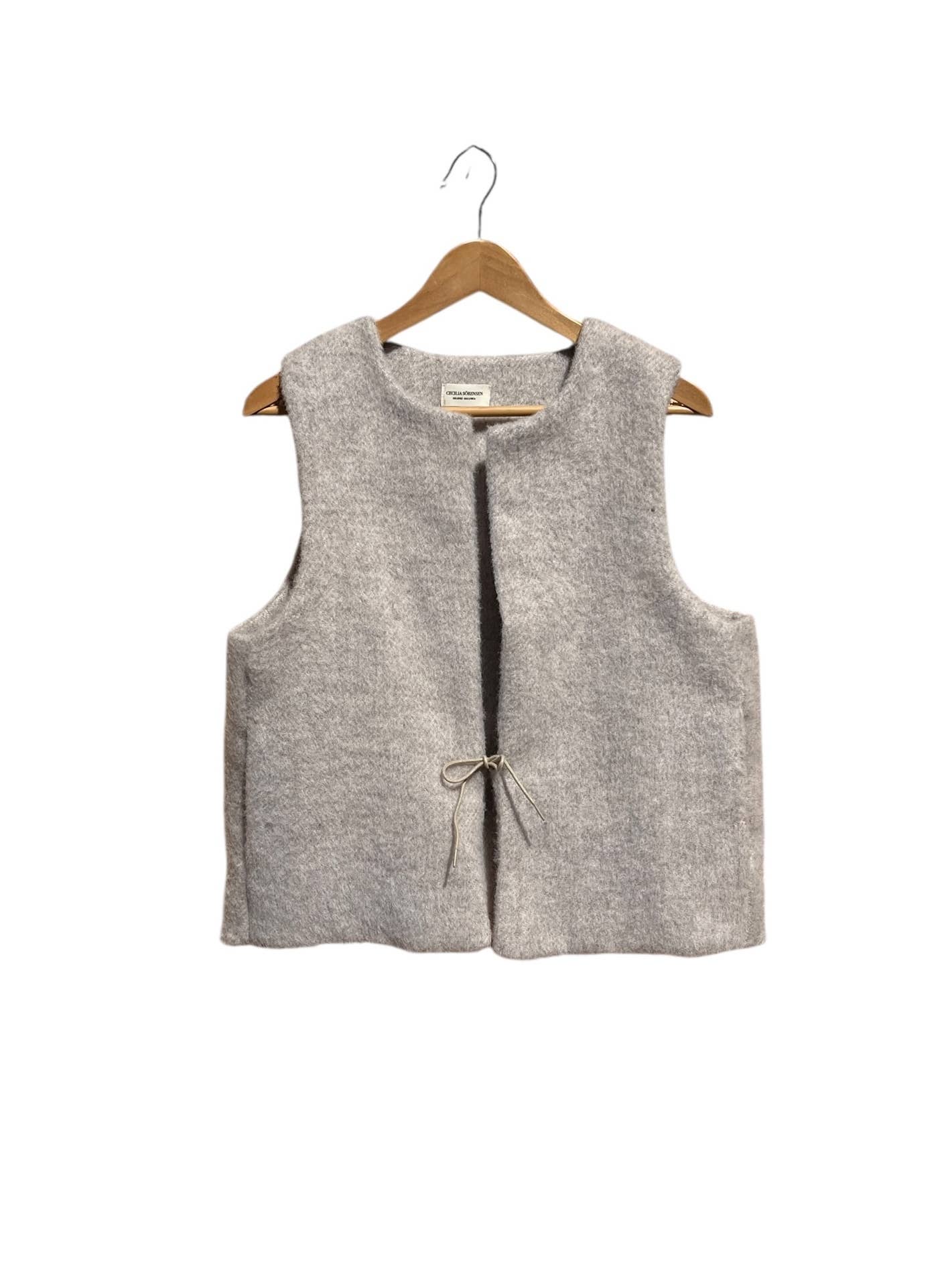 Beige sleeveless vest on a wooden hanger against a white background