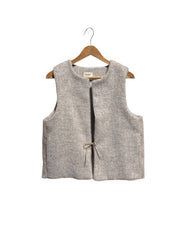 Beige sleeveless vest on a wooden hanger against a white background