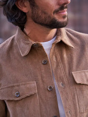 Man wearing a brown corduroy jacket with a blurred background