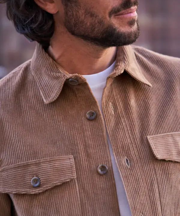 Man wearing a brown corduroy jacket with a blurred background