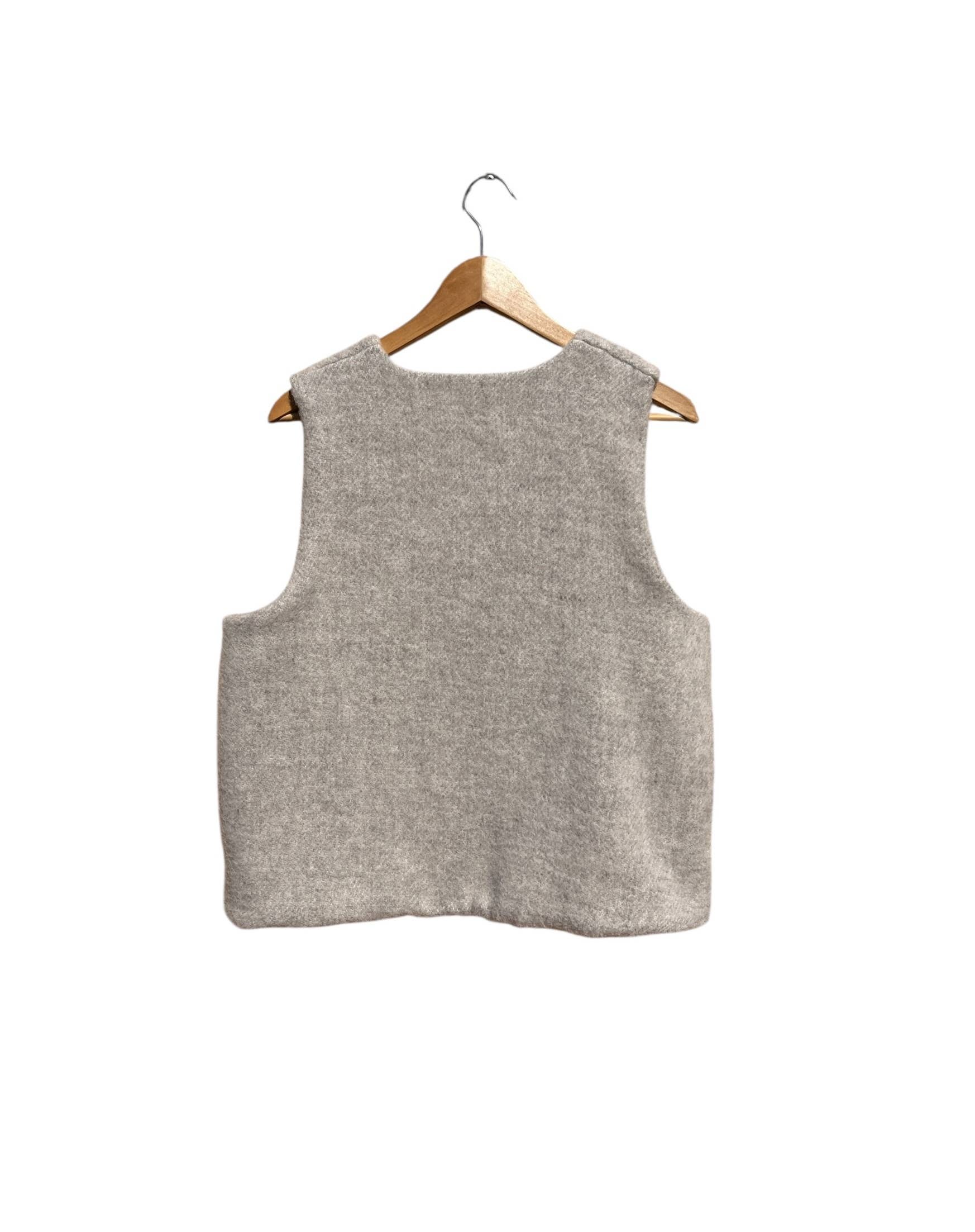Beige sleeveless vest on a wooden hanger against a white background