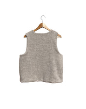 Beige sleeveless vest on a wooden hanger against a white background