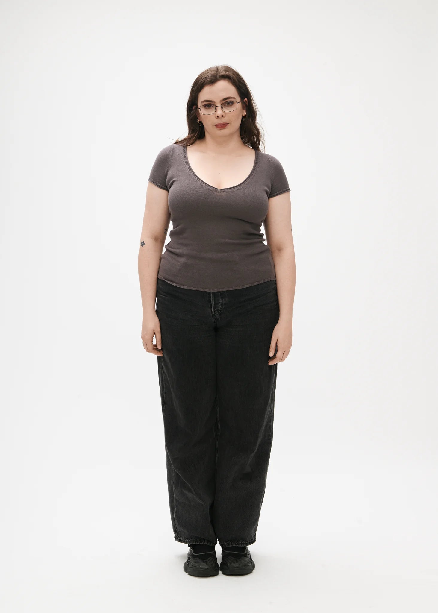 Person wearing a purple/grey t-shirt and black pants on a white background