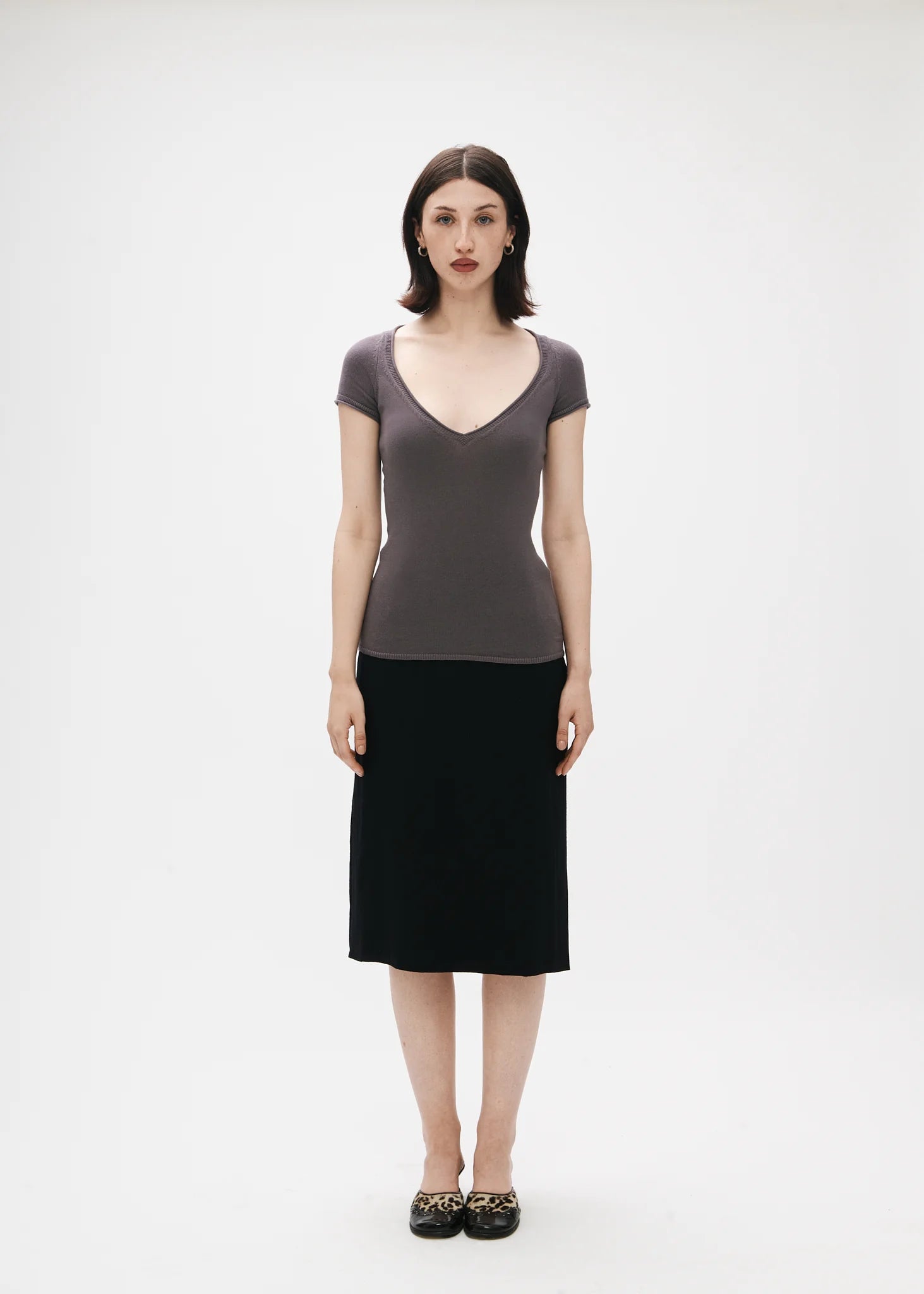 Woman wearing a gray top and black skirt on a white background