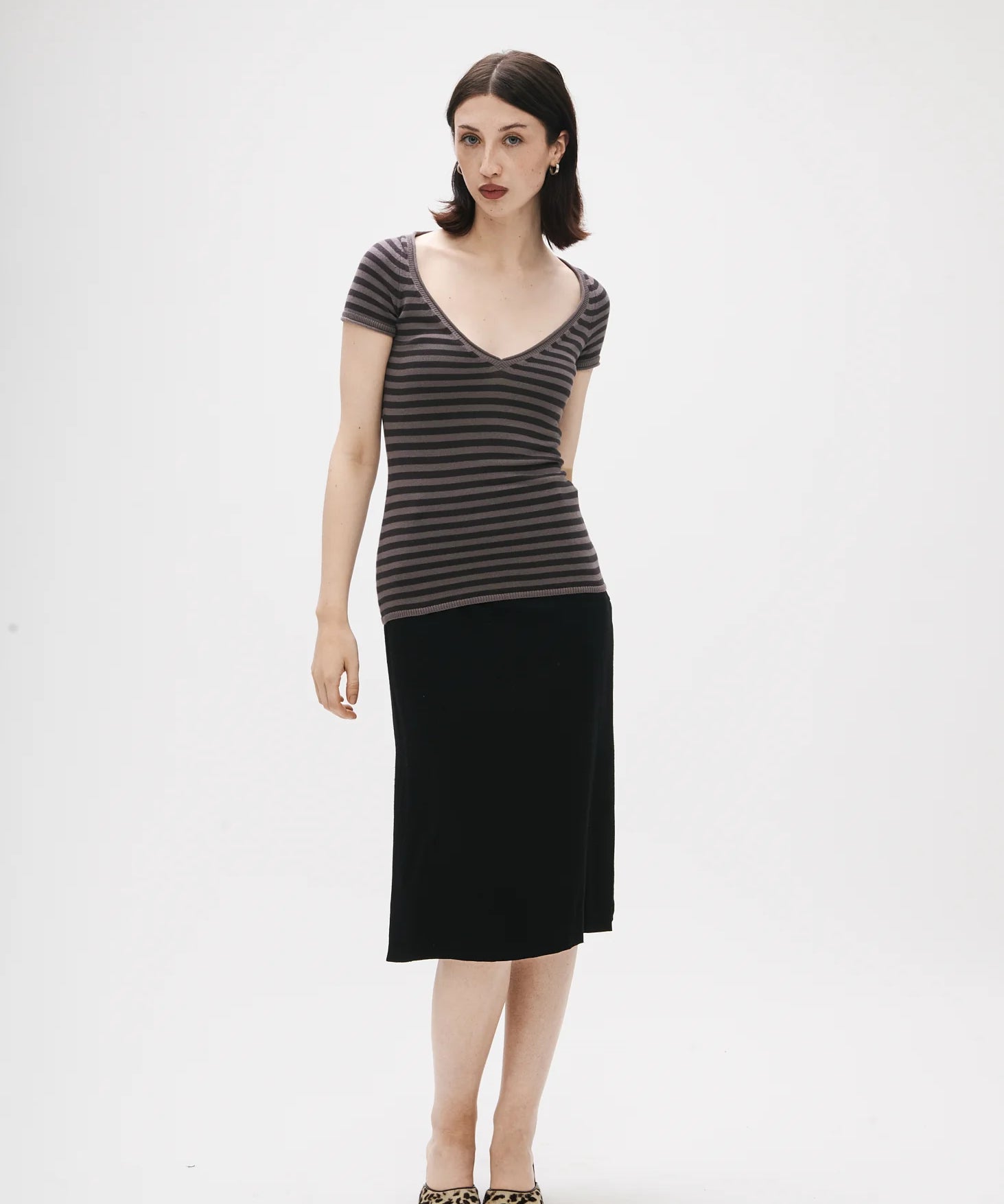 Woman wearing a striped top and black skirt on a white background