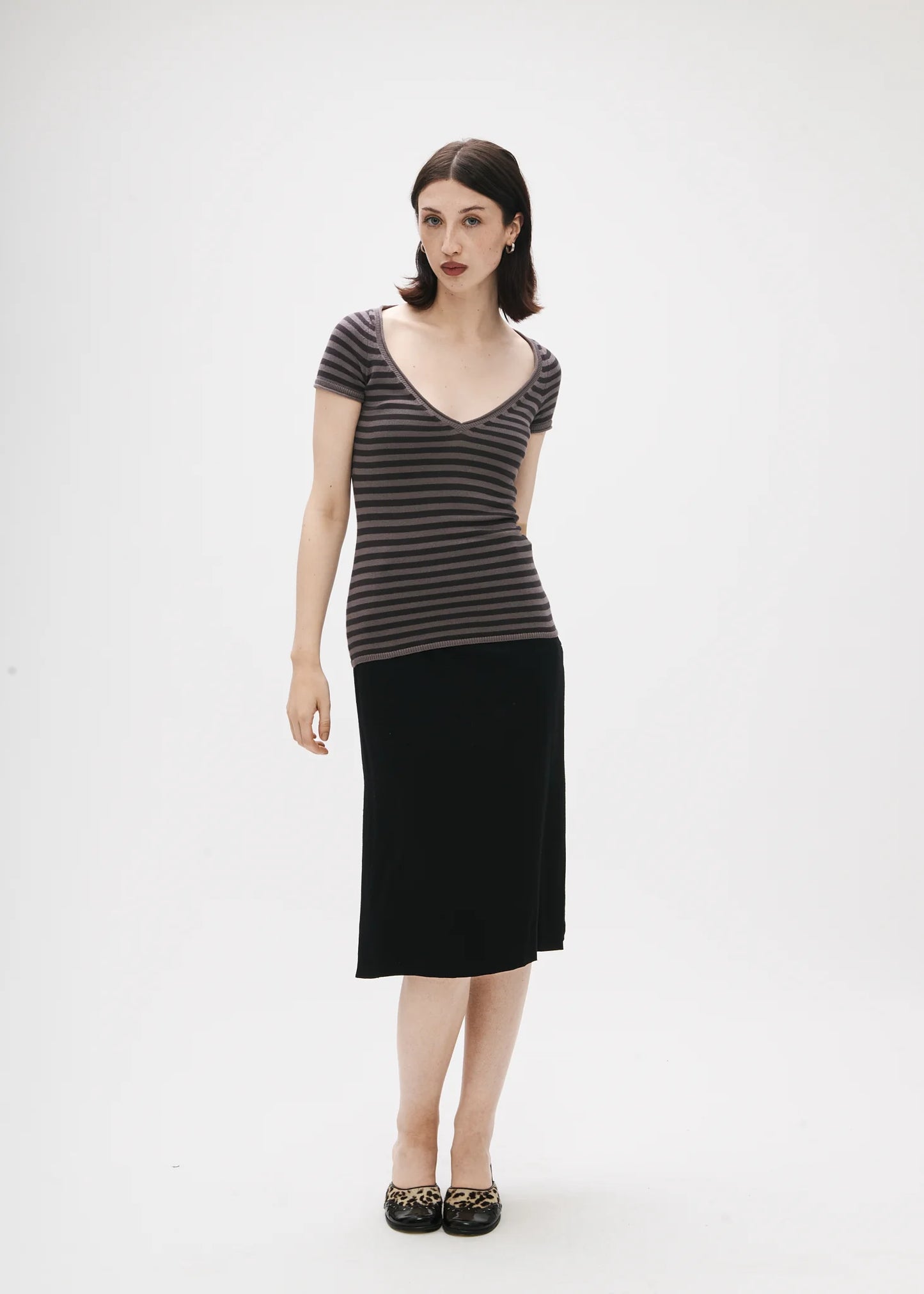 Woman wearing a striped top and black skirt on a white background