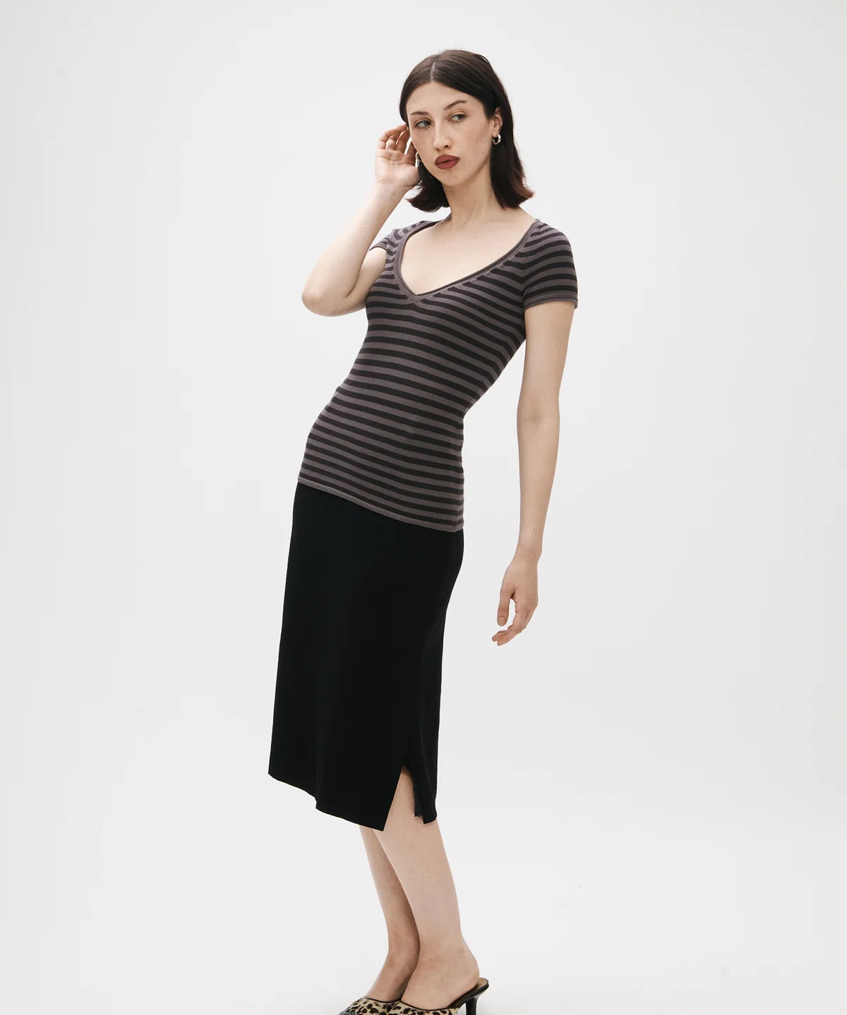 Woman wearing a striped top and black skirt on a white background