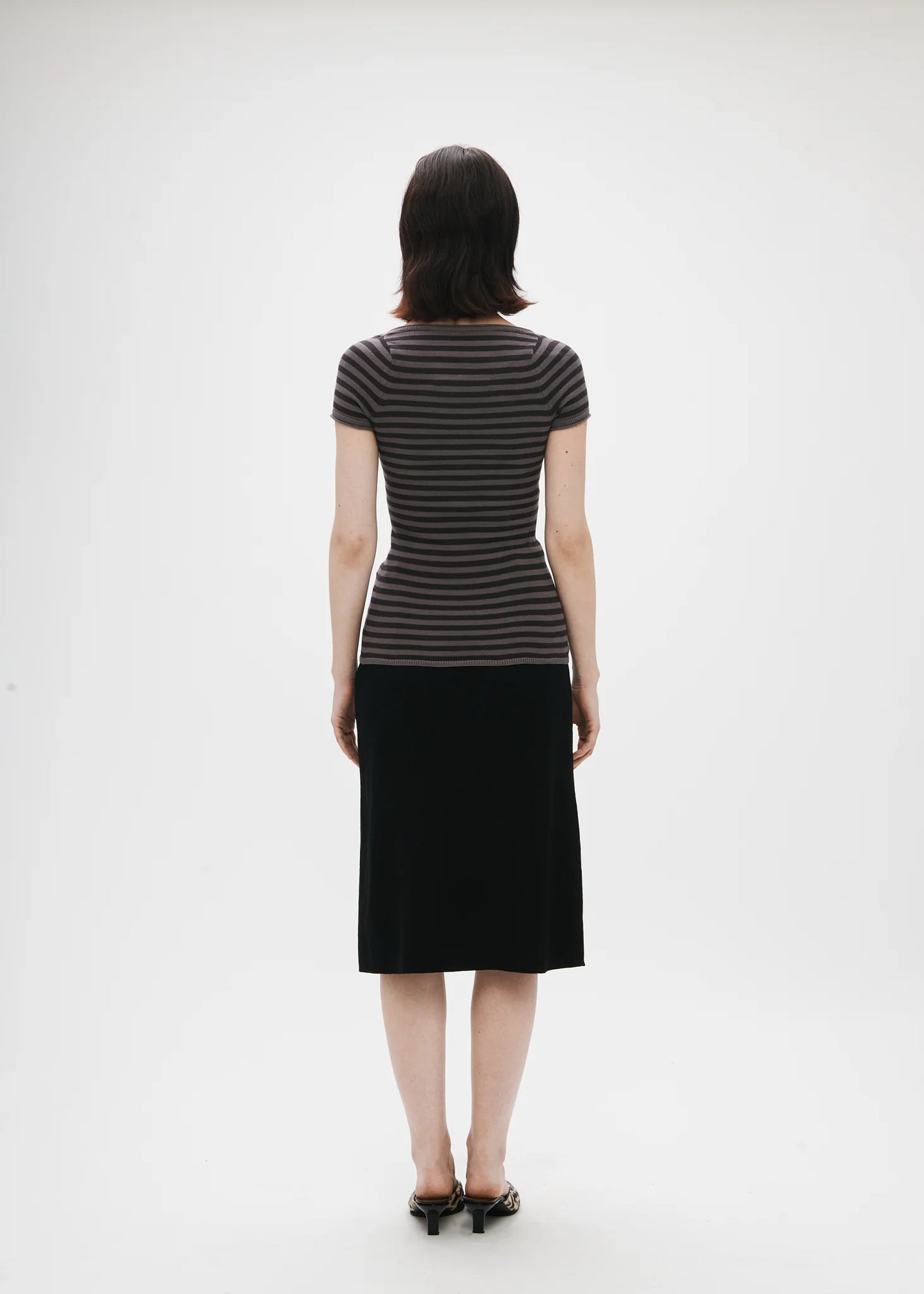 Person wearing a black and gray striped dress on a white background
