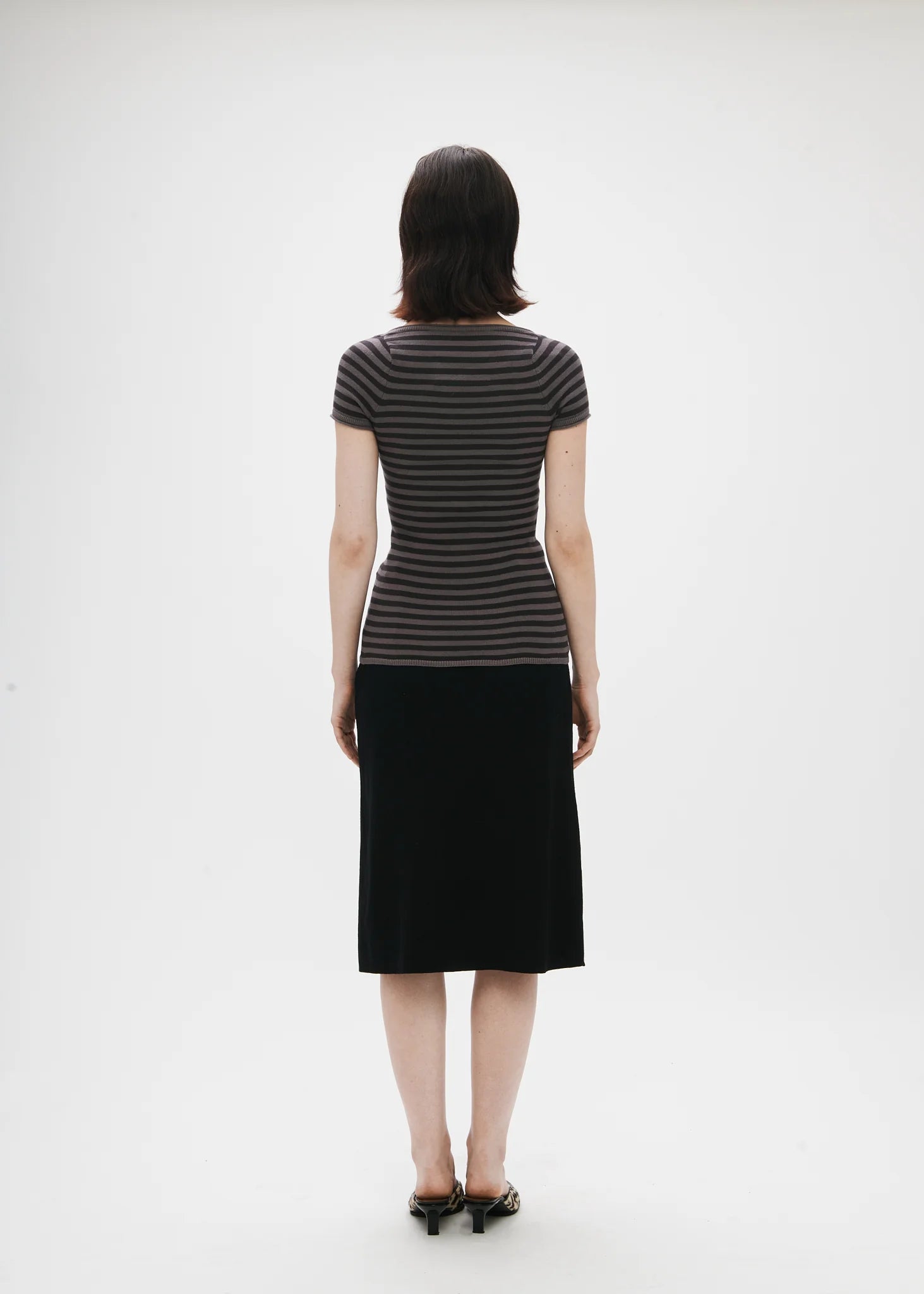 Person wearing a black and gray striped dress on a white background