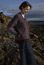 Woman in a patterned sweater standing on a rocky coastal landscape