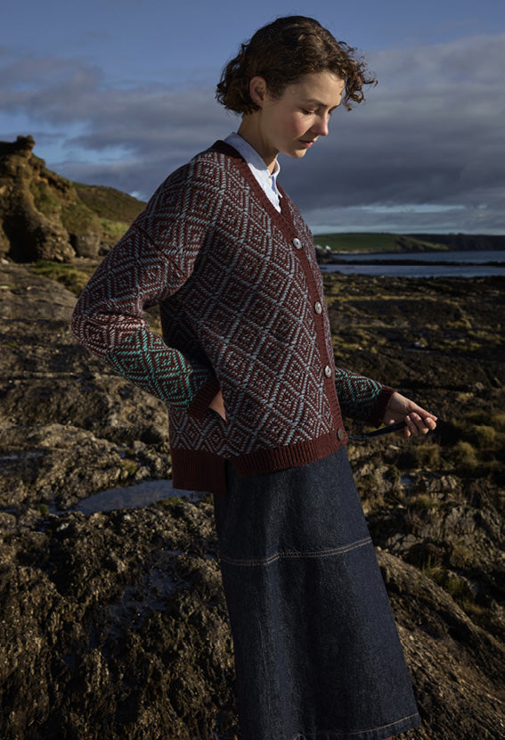 Woman in a patterned sweater standing on a rocky coastal landscape