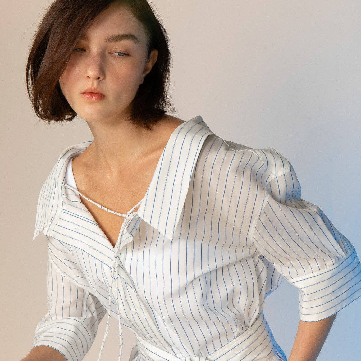 Woman wearing a white and blue striped dress against a plain background