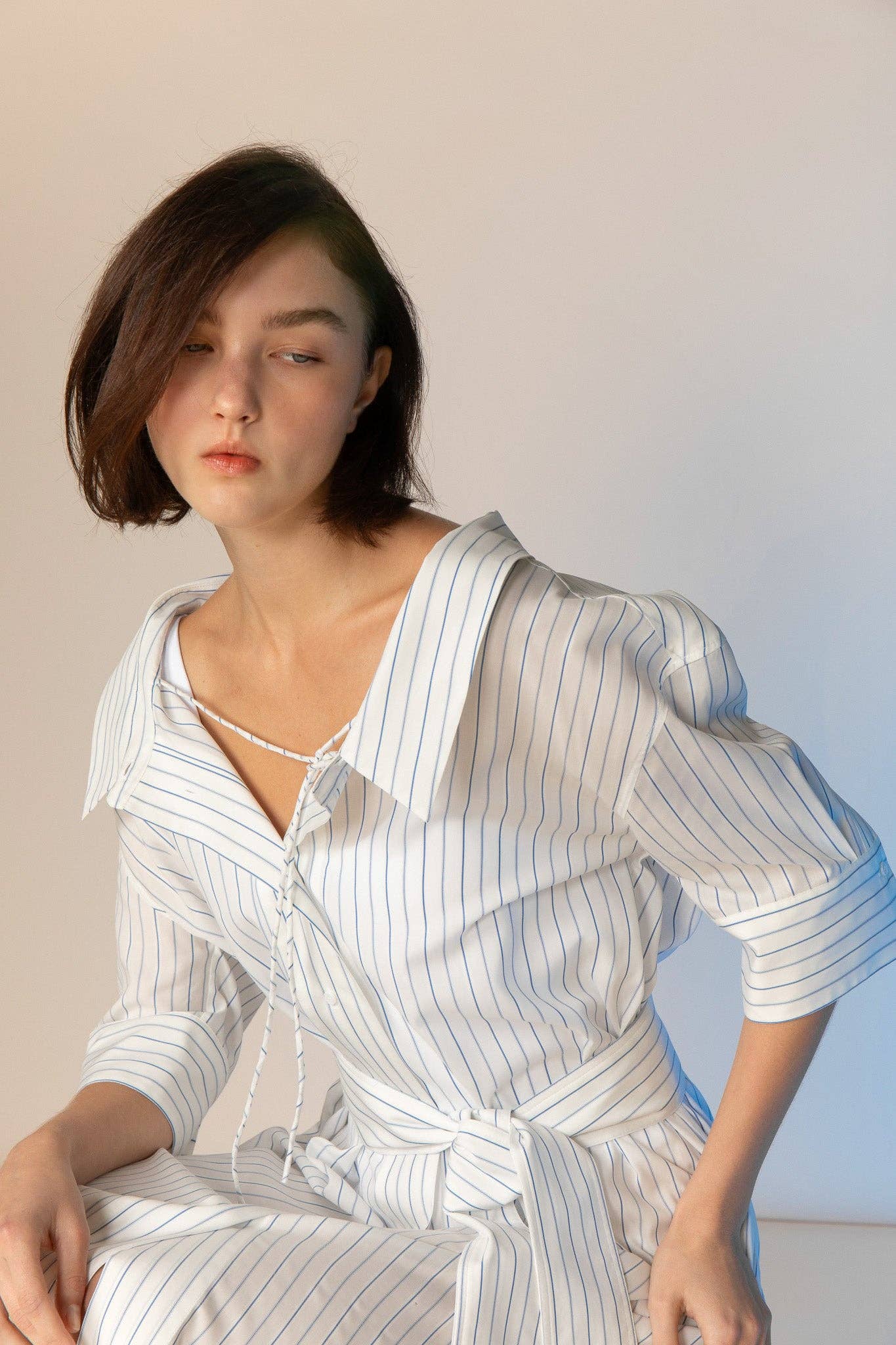 Woman wearing a white and blue striped dress against a plain background
