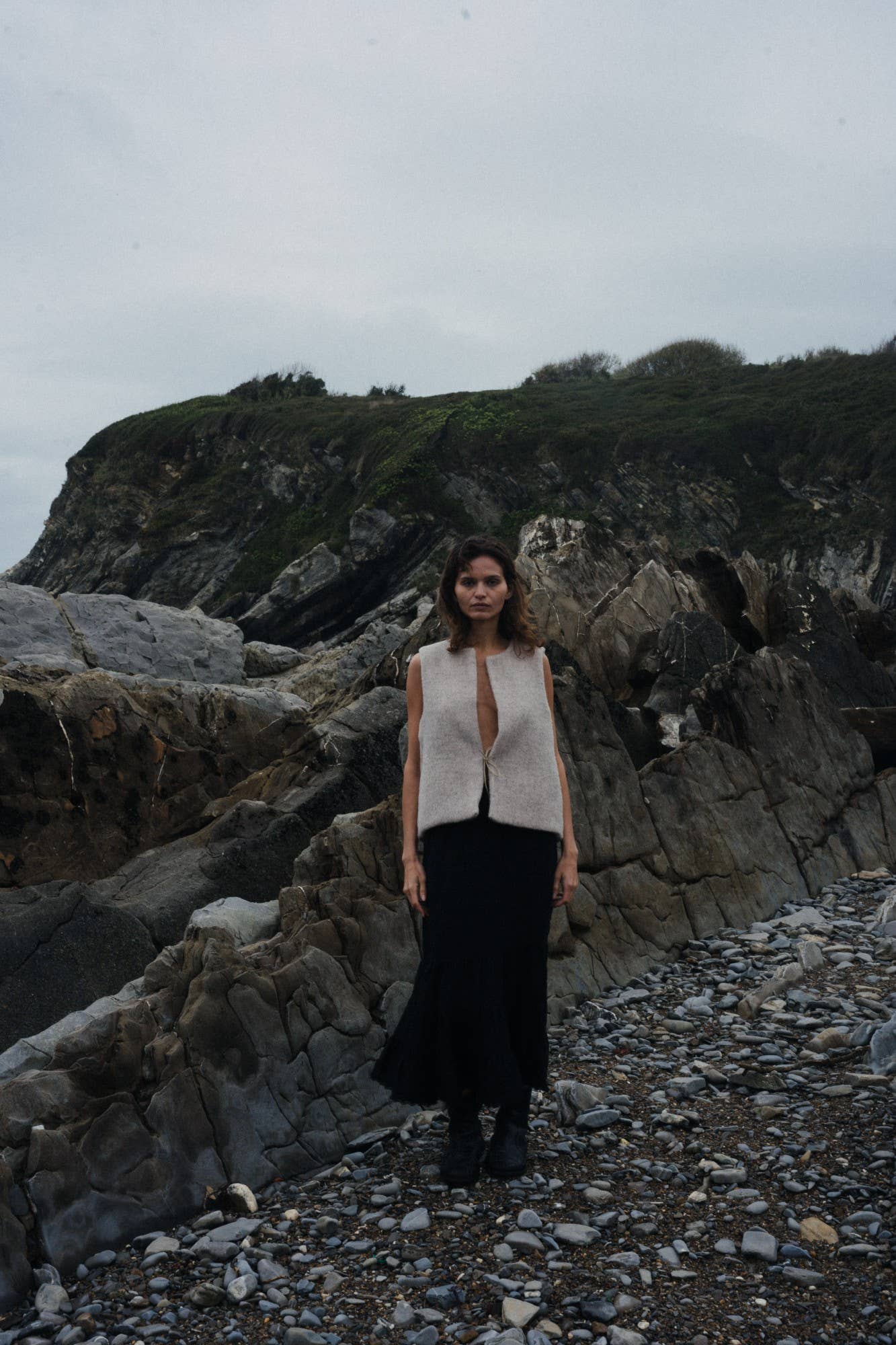 Woman standing on a rocky coastal path with cliffs in the background