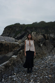 Woman standing on a rocky coastal path with cliffs in the background