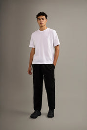 Person wearing a white t-shirt and black pants on a gray background