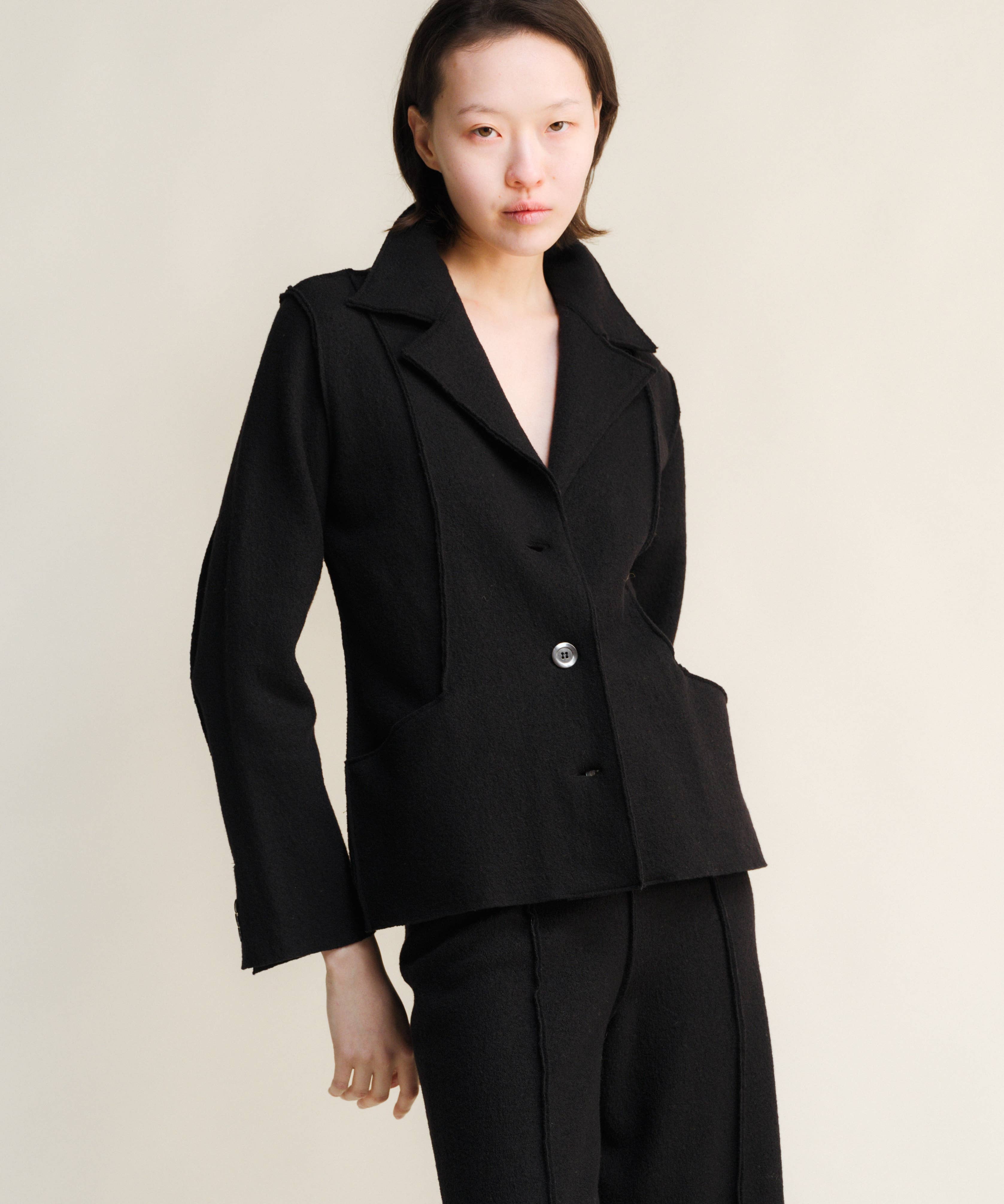 Woman wearing a black suit against a plain background
