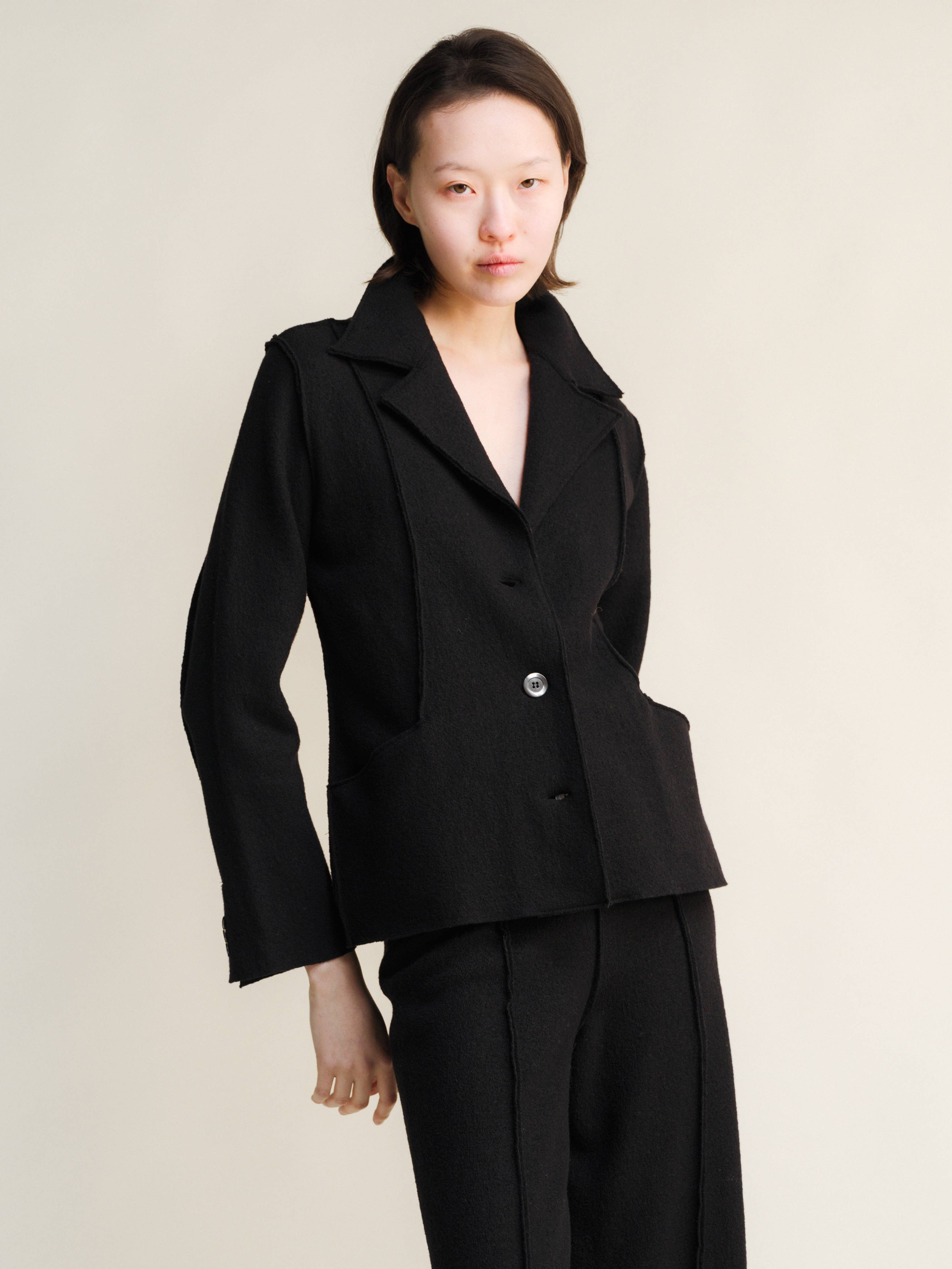 Woman wearing a black suit against a plain background
