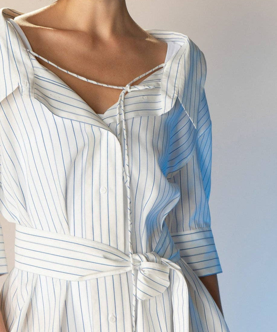 Woman wearing a white and blue striped dress with a plain background