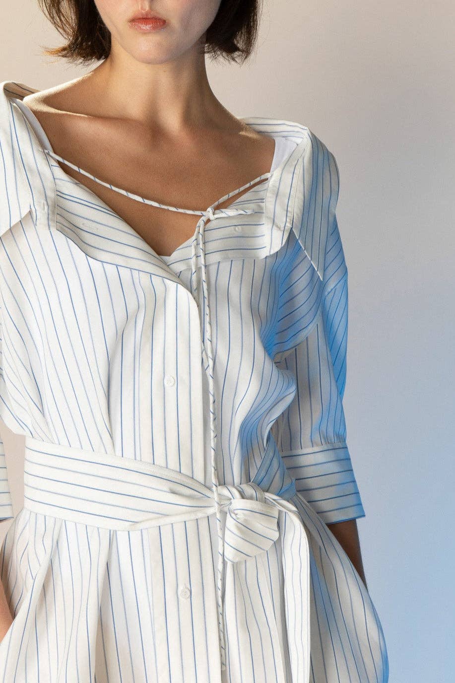 Woman wearing a white and blue striped dress with a plain background