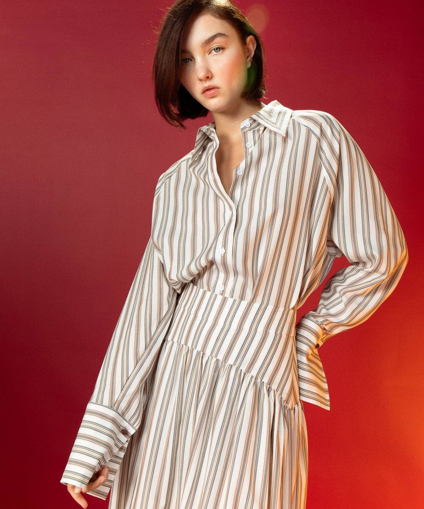 Woman wearing a striped shirt and striped skirt against a red background