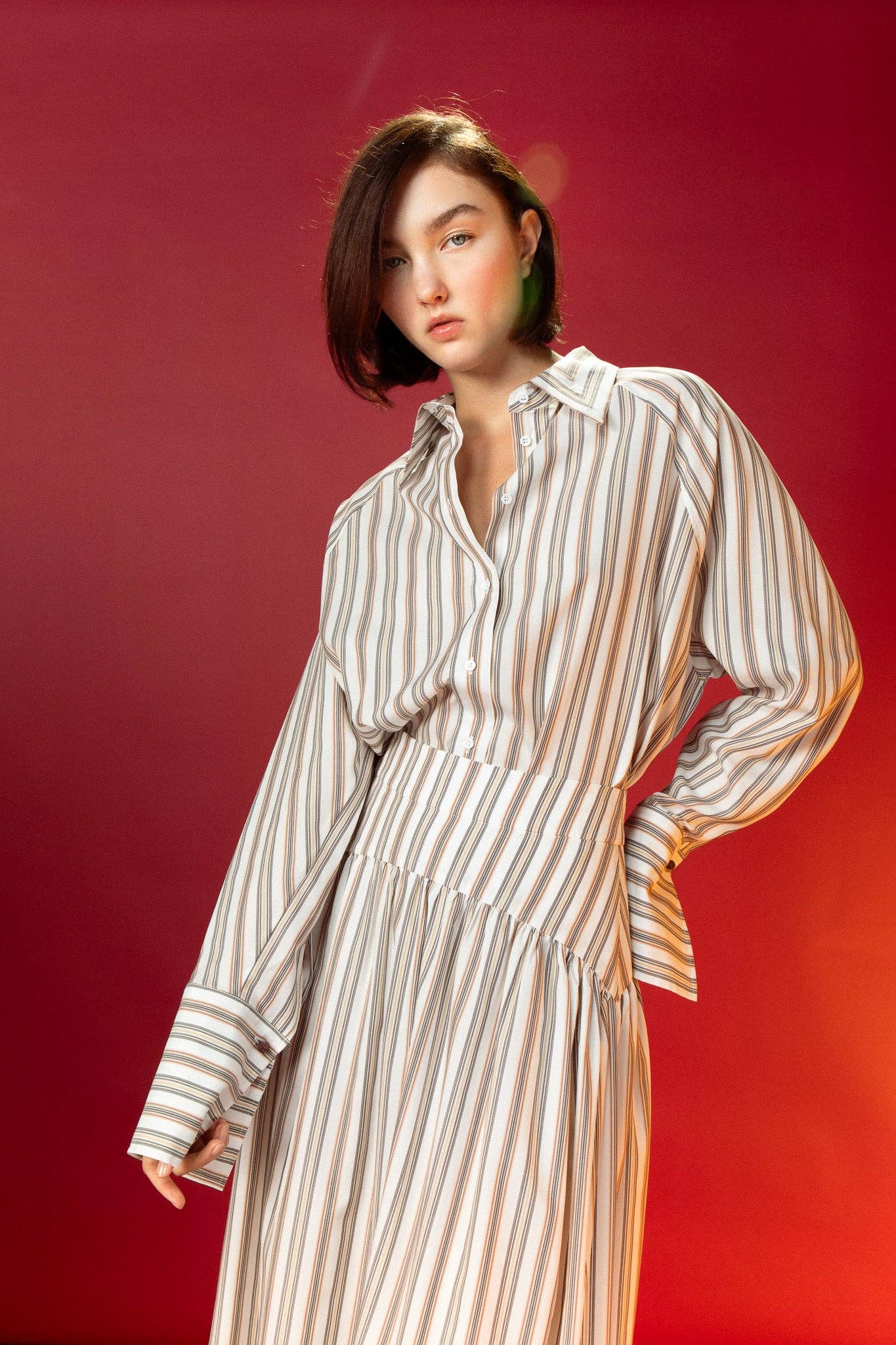 Woman wearing a striped shirt and striped skirt against a red background