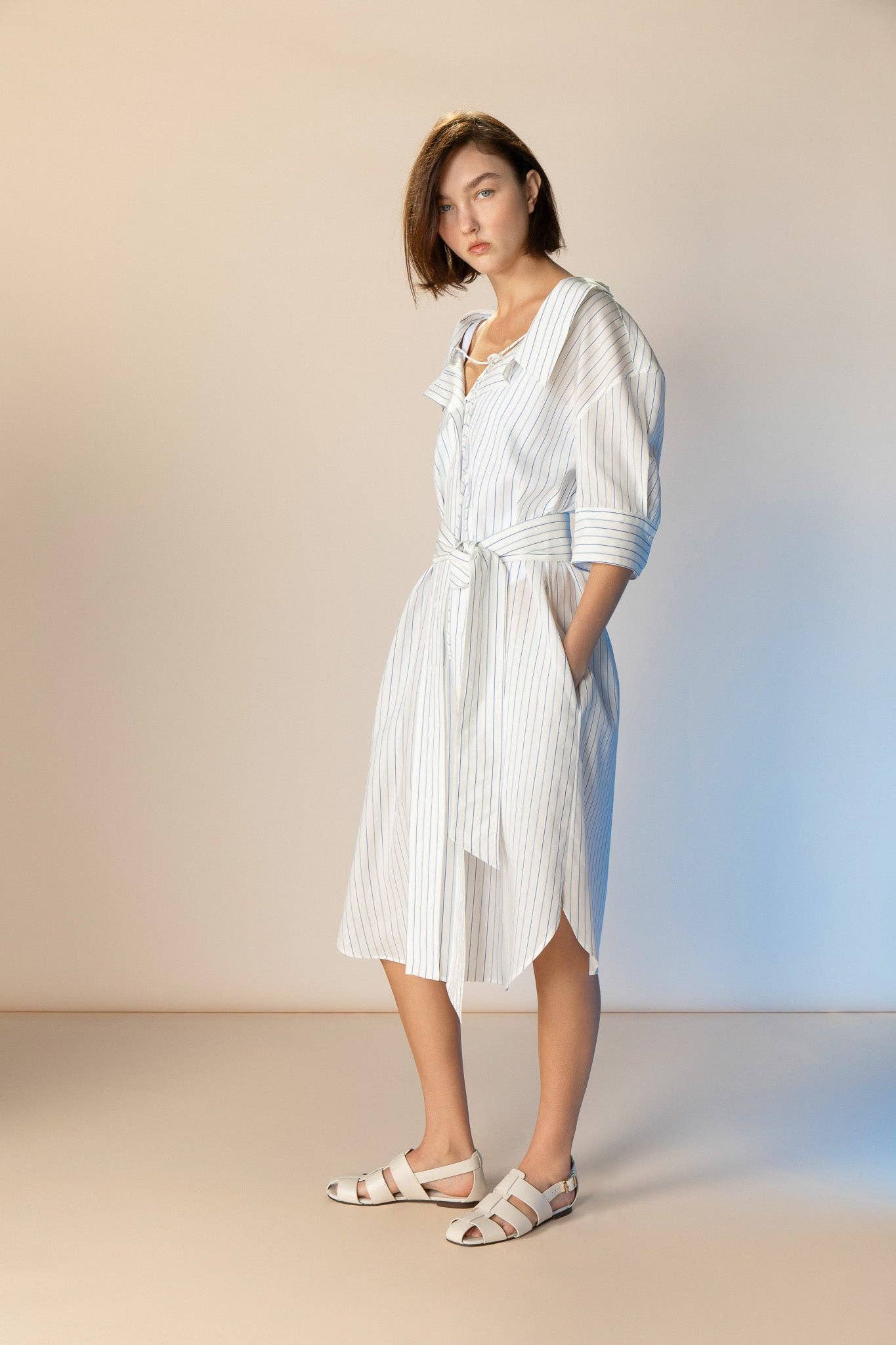 Woman wearing a white striped dress against a neutral background