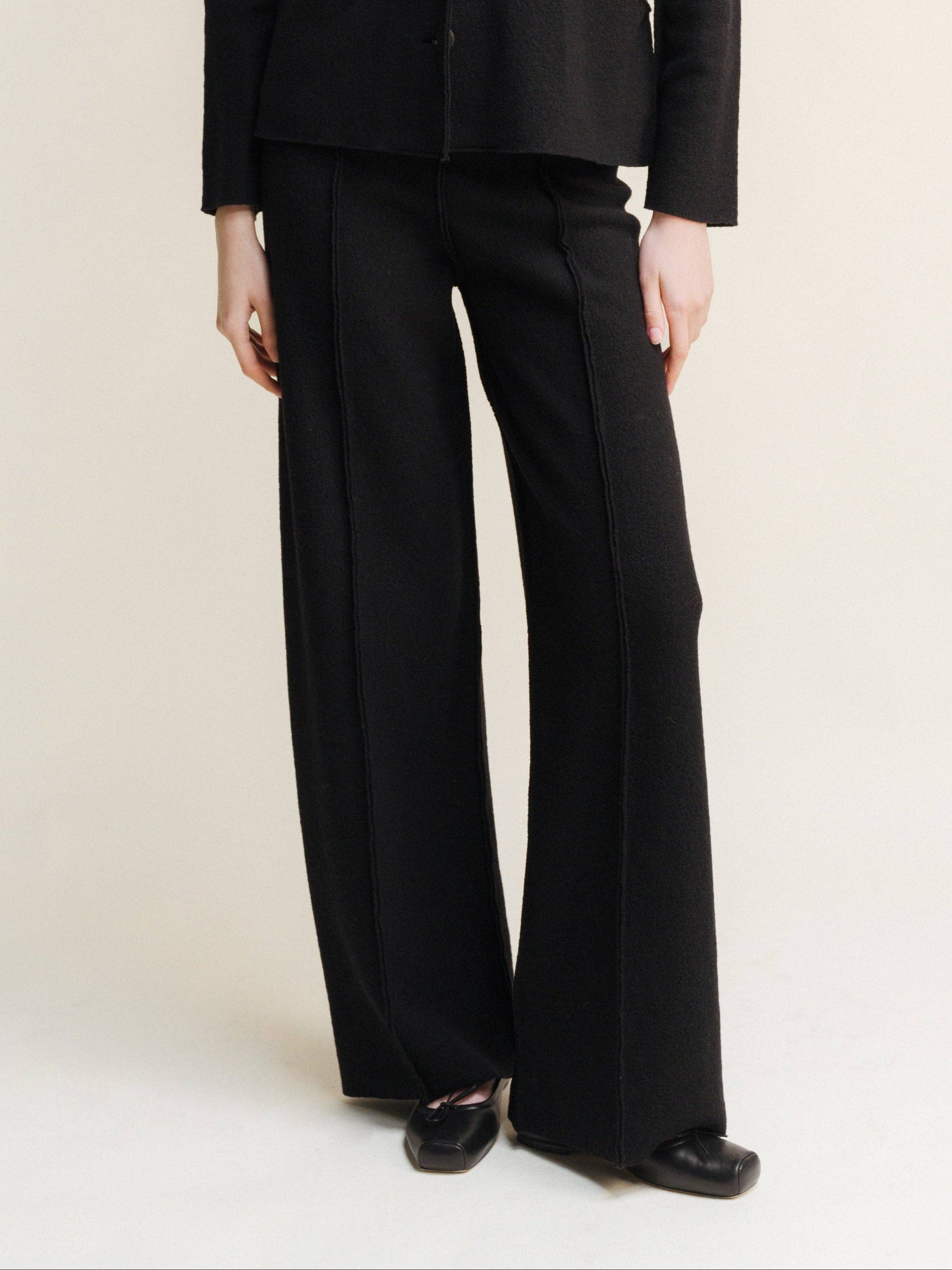 black boiled wool bootleg cut trousers with exposed seam detail down the front of both legs. 