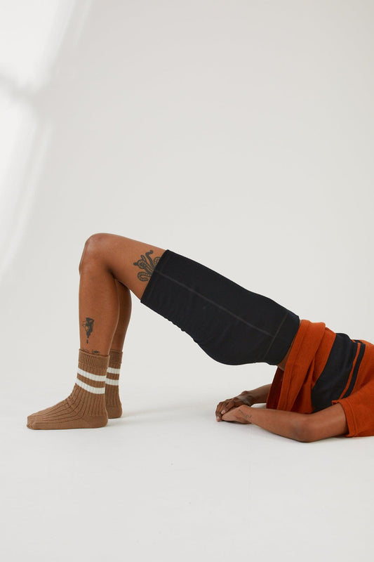 A person in a bridge position with their head out of the frame wearing merino wool socks, merino wool bike shorts and a merino wool top