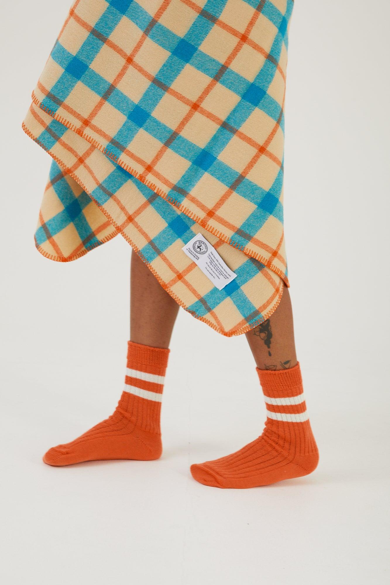 A person wearing merino wool socks with a wool bed throw wrapped around their legs