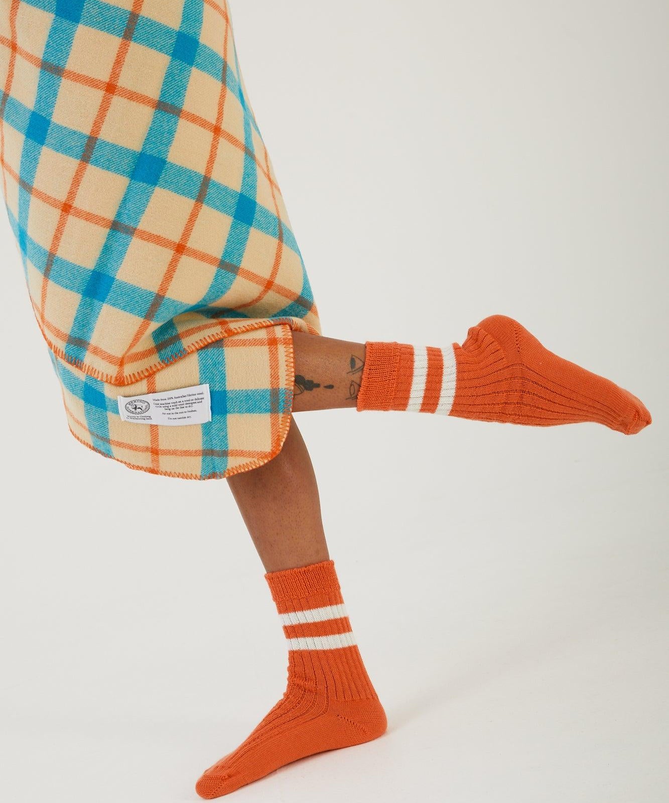 A persons legs with a wool blanket wrapped around their waist and wearing merino wool socks