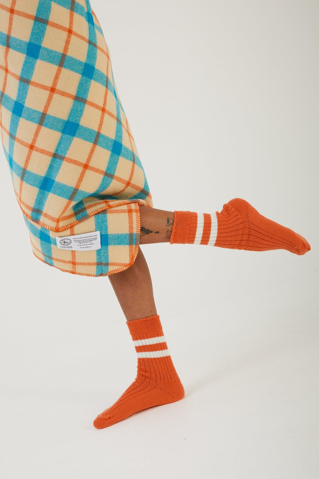 A persons legs with a wool blanket wrapped around their waist and wearing merino wool socks