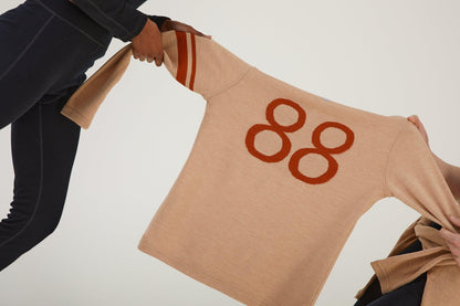 Close up of two people playing tug of war over a merino wool jumper whilst wearing merino wool clothing