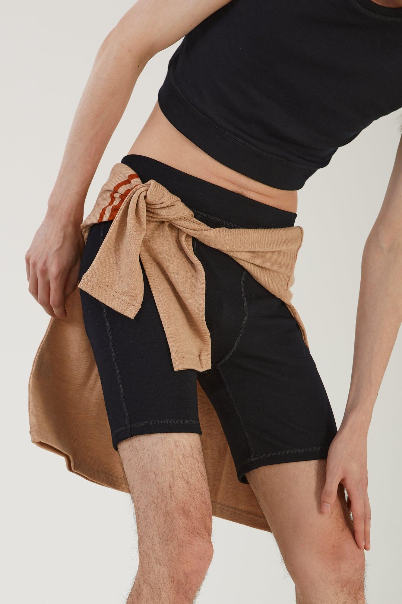 Close up of a person wearing merino wool bike shorts and a merino wool tank with a merino wool jumper tied around their waist