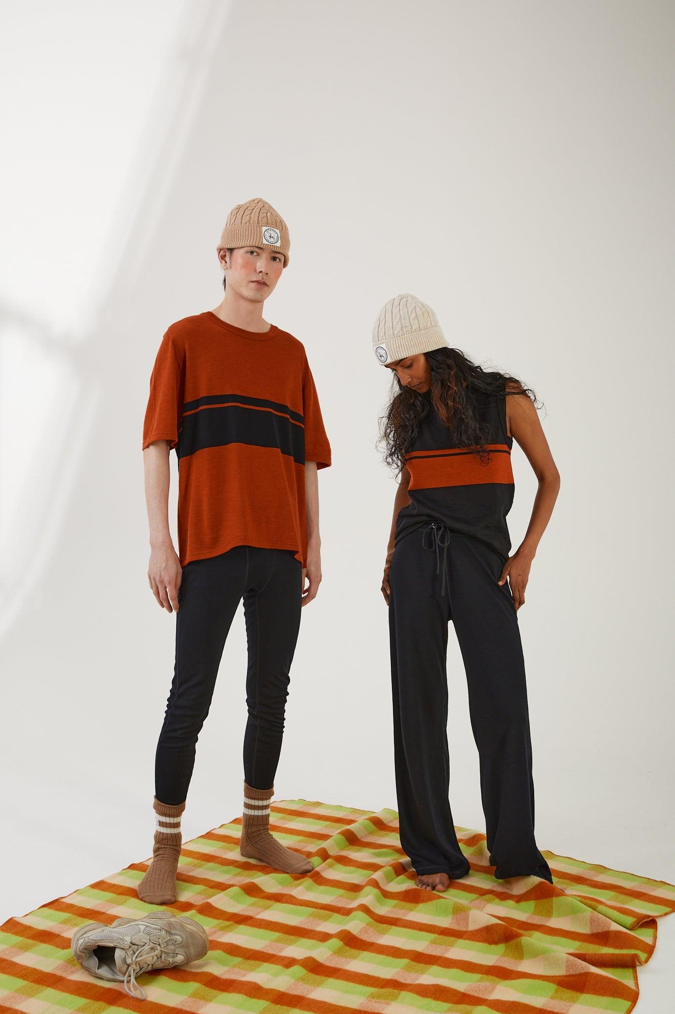 Two people standing on a wool blanket wearing merino wool clothing and merino wool accessories