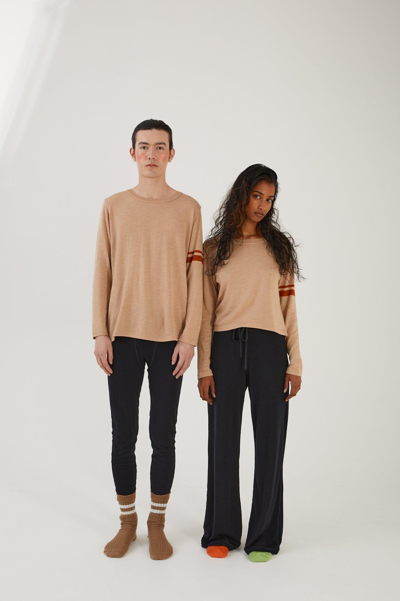 A person wearing merino wool socks, merino wool leggings and a merino wool jumper next to another person wearing merino wool socks, merino wool track pants and a merino wool jumper