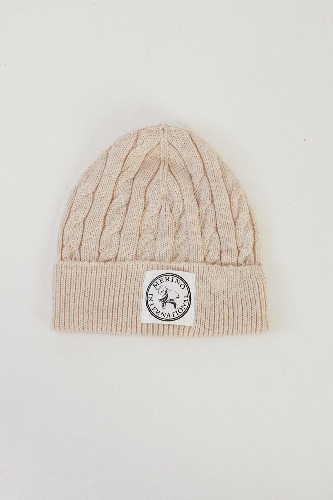 Flat lay of a merino wool cable knit beanie in ivory