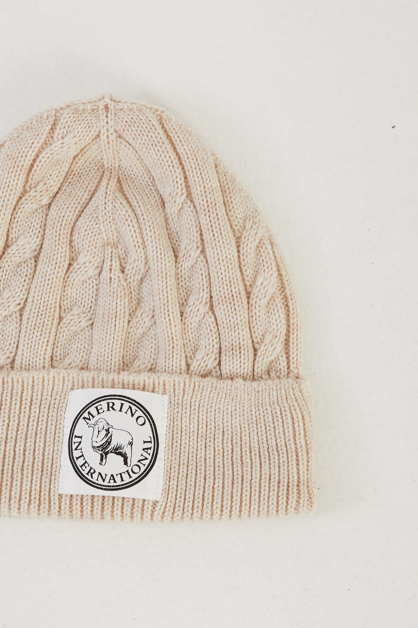 Zoomed in image of a merino wool cable knit beanie in ivory flat lay
